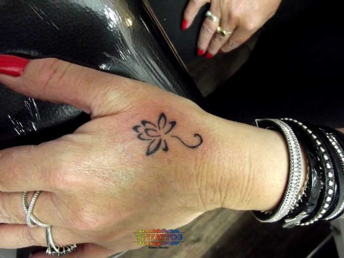 קעקוע פרח עדין בשחור לבן על גב כף היד